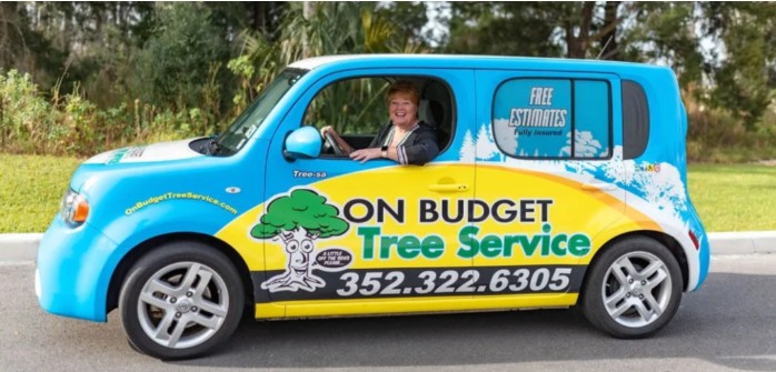 A brightly colored vehicle with a tree service advertisement, featuring a driver smiling while parked in an outdoor setting.